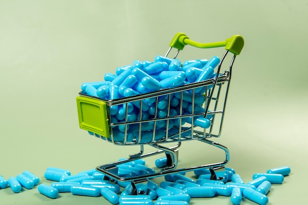 niebieska kapsułka leków w miniaturowym koszyku na zakupy