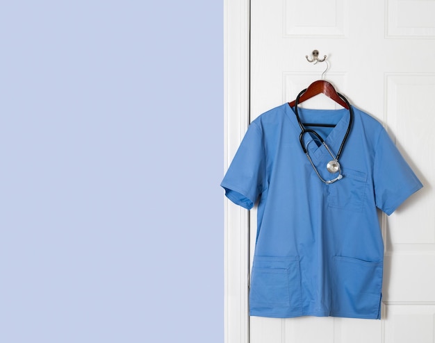 Niebieska koszula peelingowa dla lekarza wisząca na drzwiach
