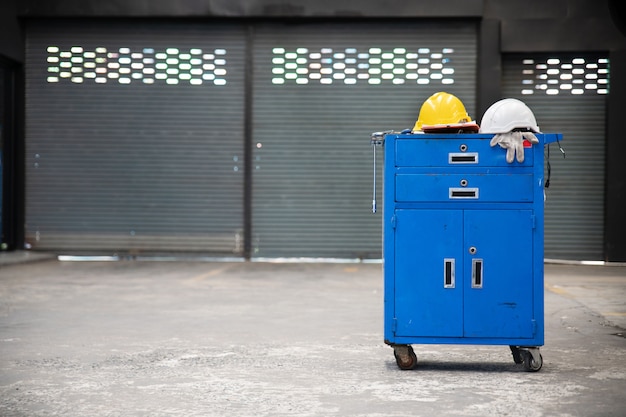 Zdjęcie niebieska metalowa szafka narzędziowa z hełmami ochronnymi, rękawicą, podkładką do dokumentów na szafce z tłem garażu. usługi naprawy samochodów.