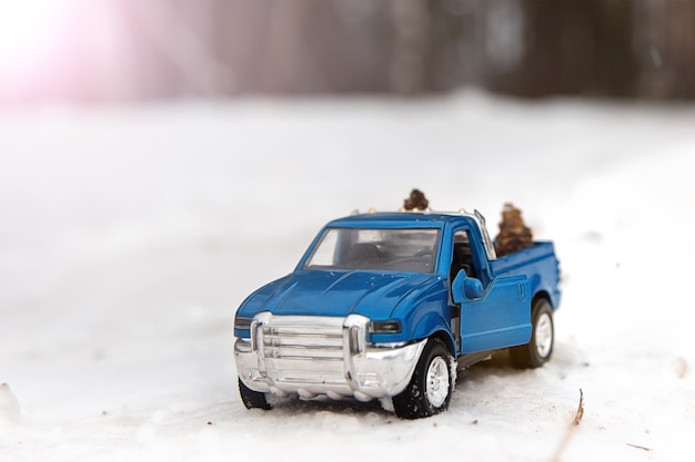 Niebieska zabawka pickup w zimowym lesie na drodze z otwartymi drzwiami