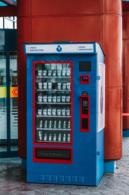 Niebieski automat z maską chirurgiczną i środkiem dezynfekującym. Sposoby ochrony