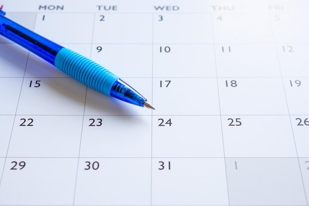 Niebieski długopis na tle strony kalendarza koncepcja spotkania planowania biznesowego