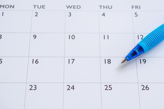 Niebieski długopis na tle strony kalendarza koncepcja spotkania planowania biznesowego