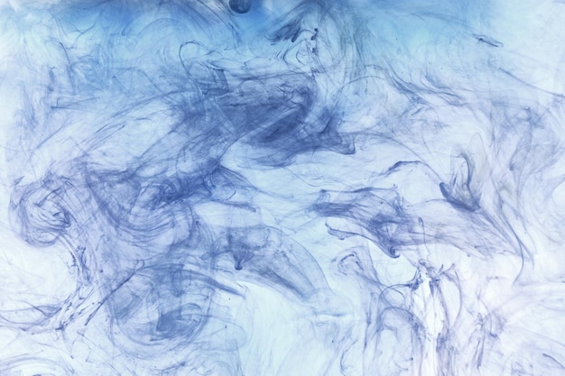 Niebieski dym na białym tle atramentu, kolorowa mgła, abstrakcyjne wirujące morze oceanu, pigment do farby akrylowej pod wodą