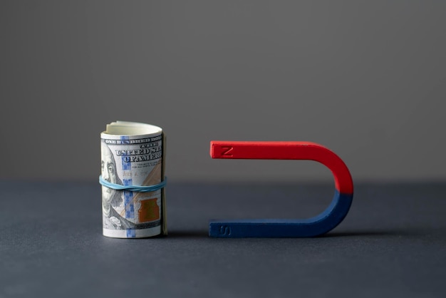 Niebieski i czerwony magnes w kształcie podkowy w pobliżu paczki gotówki w dolarach