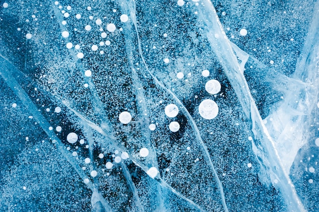 Niebieski lód z bąbelkami powietrza w zamarzniętym jeziorze. Obraz makro. Zimowe tło przyrody