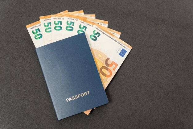Niebieski paszport z pustymi okładkami i euro w gotówce na czarnym tle Koncepcja płatności państwowych Podróż budżetowa