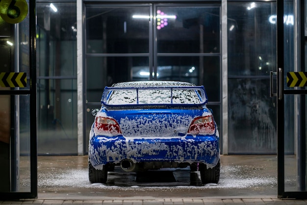 Niebieski samochód w automatycznej myjni w nocy