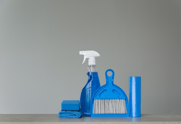 Zdjęcie niebieski zestaw do czyszczenia na neutralnym tle: rozpyl detergent, worki na śmieci, ściereczki, gąbkę, miarkę i miotłę. skopiuj miejsce.