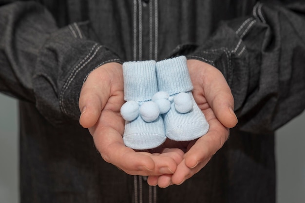 Niebieskie buciki niemowlęce w ręku ojca
