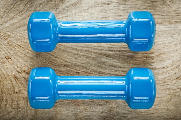 Zdjęcie niebieskie hantle ciężary na drewnianej desce sportowej koncepcji szkolenia.
