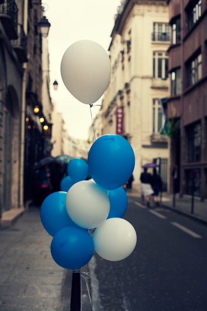 Niebieskie i białe balony z heliem przywiązane do słupka na ulicy w mieście