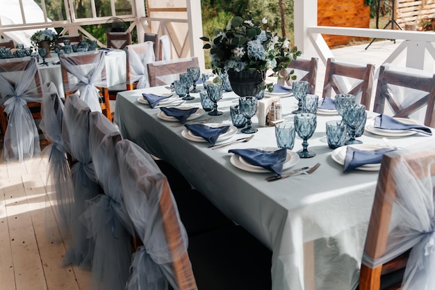 Niebieskie kieliszki i sztućce na świątecznym stole z kwiatami Obsługa i wystrój weselnego stołu