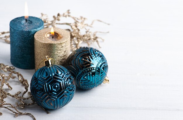 Niebieskie kule, złote świece zapachowe i świąteczne zabawki na drewnianym rustykalnym