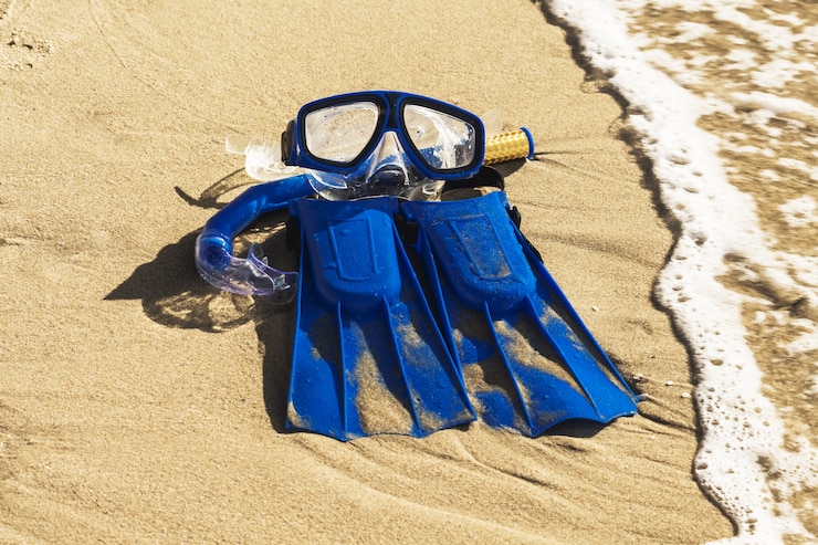 Zdjęcie niebieskie płetwy, maska, fajka do surfowania na piaszczystej plaży. koncepcja plaży.