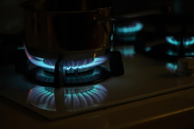 Zdjęcie niebieskie płomienie gazu płonące z kuchennego pieca gazowego