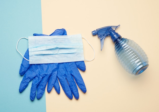 Niebieskie rękawiczki i maska tekstylna wielokrotnego użytku, niebieska butelka na dezynfektor
