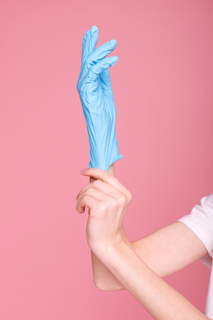 Niebieskie rękawiczki medyczne na ramionach dziewczyny na różowej powierzchni