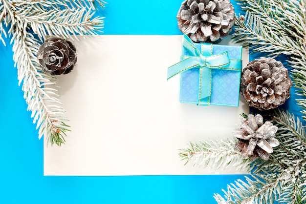 Zdjęcie niebieskie tło bożonarodzeniowe, ramka z gałązkami jodły, pudełko i srebrne dekoracje