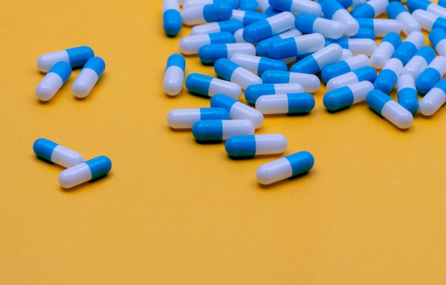Niebieskobiałe tabletki w kapsułkach na żółtym tle Baner apteki internetowej Grupa tabletek w kapsułkach