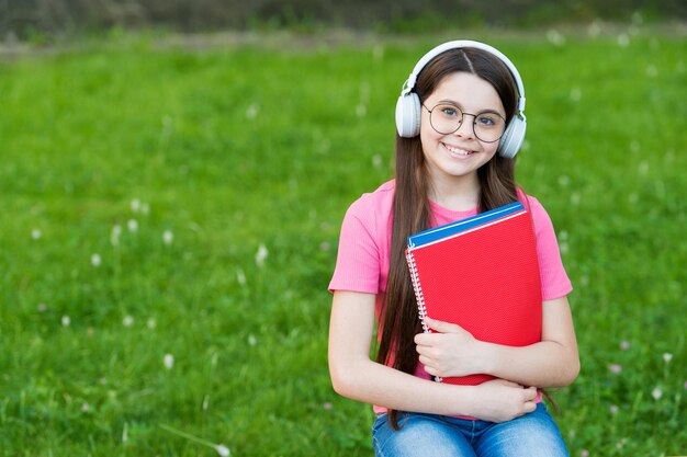 Niedrogi e-learning Szczęśliwe dziecko słucha kursu e-learningowego Mała dziewczynka uczy się online w plenerze E-learning i nauka Lekcja muzyki Edukacja na odległość Szkolenie na odległość E-learning to przyszłość