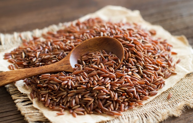 Niegotowane Czerwony ryż z drewnianą łyżką z bliska