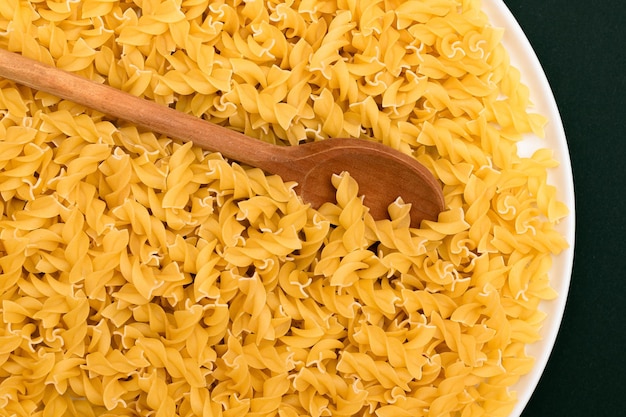 Niegotowane makarony fusilli z drewnianą łyżką