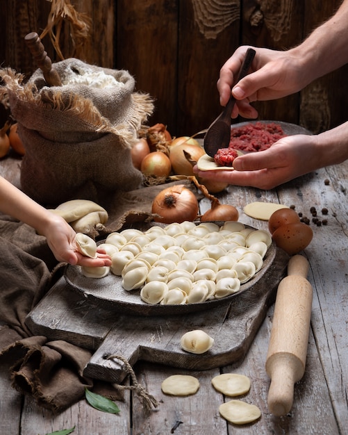 Niegotowane pierogi mięsne - rosyjskie pelmeni na desce do krojenia i składnikach