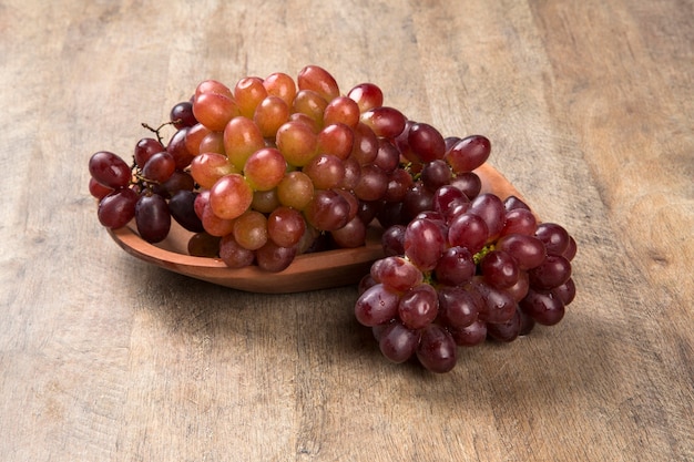 Niektóre czerwone winogrona w drewnianej doniczce na drewnianej powierzchni widziane z góry