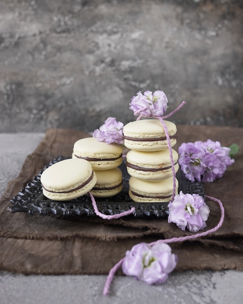 niektóre żółte macarons na szarym tle, ozdobione kwiatami. Francuskie wypieki