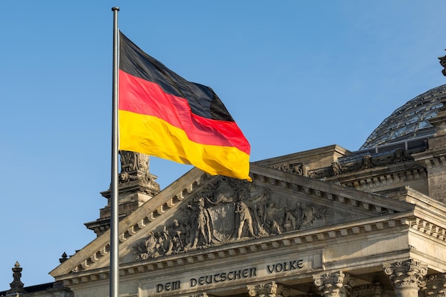 Niemiecka flaga macha przed budynkiem Reichstagu w Berlinie