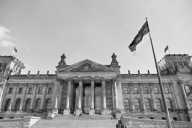 Zdjęcie niemieckie flagi powiewają na wietrze w słynnym budynku reichstagu, siedzibie niemieckiego parlamentu deutscher bundestag w słoneczny dzień z błękitnym niebem i chmurami w centrum berlina, dzielnica mitte niemcy