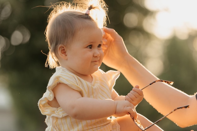 Zdjęcie niemowlę w żółtym ubraniu bawi się okularami przeciwsłonecznymi w parku