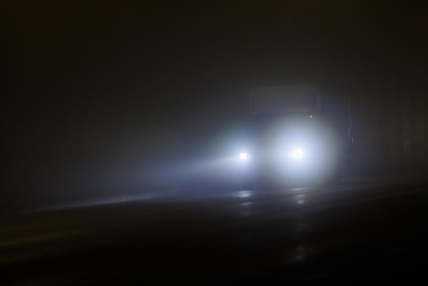 Nieostre samotny minivan poruszający się po pustej nocnej mglistej drodze