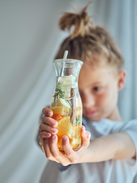 Zdjęcie nieostrość dziecka pokazującego szklankę smacznej lemoniady z różnych owoców cytrusowych i przypraw