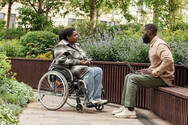 Niepełnosprawna kobieta rozmawiająca z przyjacielem w ogrodzie