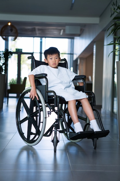 Niepełnosprawny chłopiec pacjenta na wózku inwalidzkim w szpitalnym korytarzu