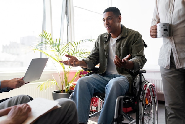 Zdjęcie niepełnosprawny mężczyzna na wózku inwalidzkim wykonujący pracę biurową