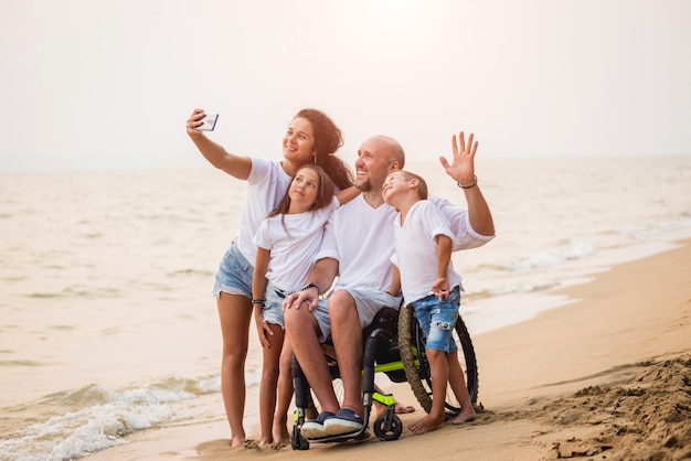 Niepełnosprawny Mężczyzna Na Wózku Inwalidzkim Z Rodziną Na Plaży.