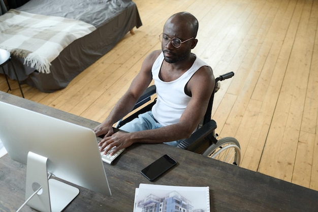 Niepełnosprawny mężczyzna pracujący na komputerze w domu