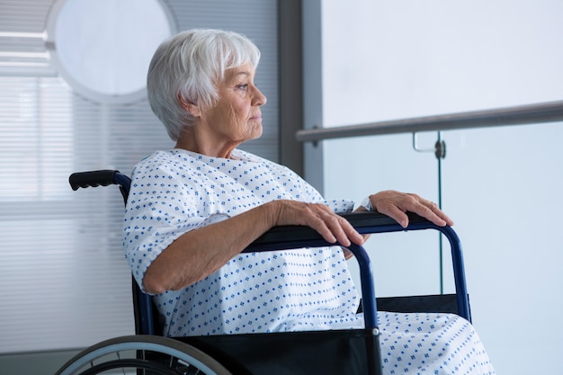 Niepełnosprawny starszy pacjent na wózku inwalidzkim na korytarzu szpitalnym
