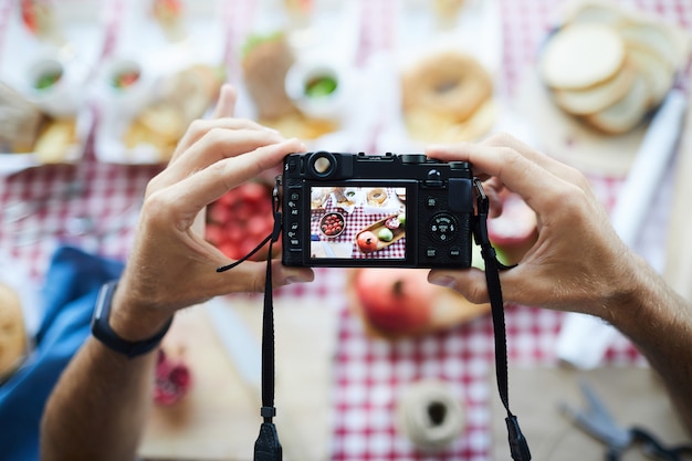 Nierozpoznany fotograf trzymający aparat cyfrowy