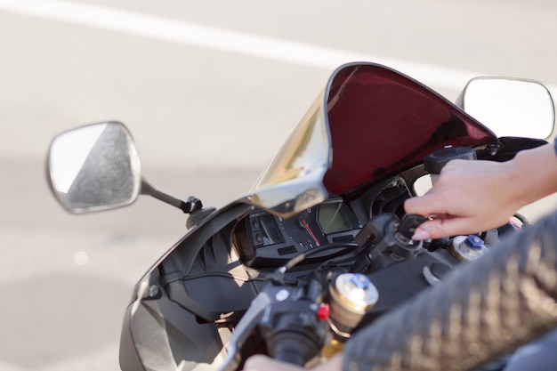 Nierozpoznawalna kobieta motocyklistka włącza silnik motocykla