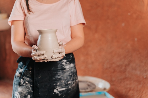 Zdjęcie nierozpoznawalna osoba chwytająca świeżo zrobiony wazon na kole garncarskim