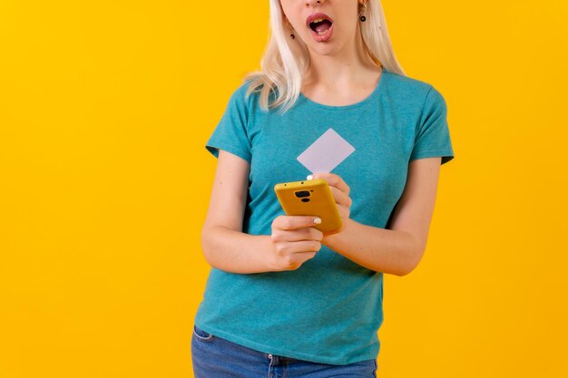 Nierozpoznawalna osoba w płatności online kartą na żółtym tle studia telefonicznego