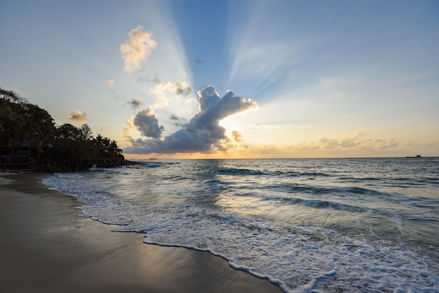 Niesamowita piaszczysta tropikalna plaża z sylwetką tropikalnej plaży - wschód lub zachód słońca morze dramatyczne niebo