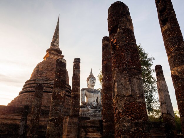 Niesamowita scena wielkiego posągu Buddy i starych starożytnych ruin w świątyni Wat Mahathat w rejonie Parku Historycznego Sukhothai, wpisanego na Listę Światowego Dziedzictwa UNESCO w Tajlandii.