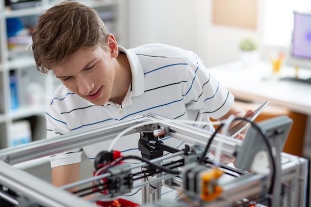 Niesamowite Technologie. Wesoły Młody Inżynier Drukuje Model 3d Papryki I Uśmiecha Się Radośnie, Zadowolony Z Efektu