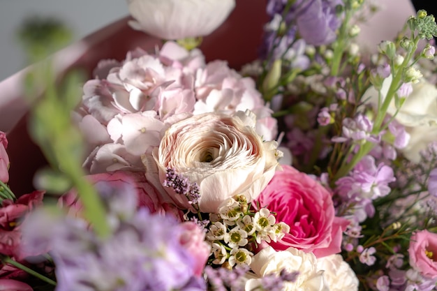 Zdjęcie niesamowity delikatny bukiet z różowymi fioletowymi kwiatami jaskiera i drobnymi białymi różyczkami w kartoniku z różową wstążką piękny bukiet wiosennych kwiatów prezent wielkanocny sezonowe wiosenne kwiaty