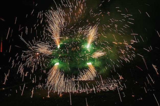 Niesamowity pokaz ognia w nocy na festiwalu lub weselu Tancerze ognia huśtają się wirując zielonym ogniem, a mężczyzna żongluje jasnymi iskrami podczas nocnego pokazu ognia i rozrywki
